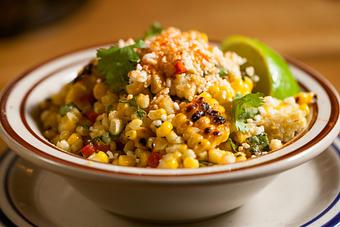 Product: Grilled corn cut off the cob served in a small white bowl and topped with crumbled cheese, jalapeno slices and a lime wedge - Bub City in Rosemont, IL Barbecue Restaurants