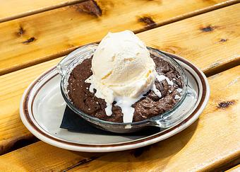 Product: Circular brownie served in a clear glass dish topped with a scoop of vanilla ice cream - Bub City in Rosemont, IL Barbecue Restaurants