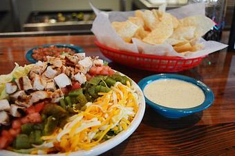 Product: Mexi-Cobb Salad with fajita chicken, green chiles, cheese, avocados, and tomatoes, on a bed of salad greens - Chuy's in Lubbock, TX Tex Mex Restaurants