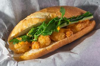 Product: Large crisply fried shrimps infused with creamy tangy sauce, topped with cilantro and cucumber in a demi baguette - Eurasian Bistro in Argonaut Village - Pensacola, FL Vietnamese Restaurants