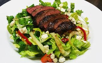 Product: Tender grilled steak with grilled onions and peppers - Served on a bed of romaine with blue cheese crumbles. 13.99 - Finnegan's Grill in Ashburn, VA American Restaurants