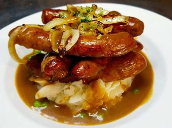 Product: Grilled Irish sausage over mashed potatoes with caramelized onions, peas and Guinness gravy. - Finnegan's Grill in Ashburn, VA American Restaurants