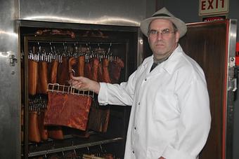 Product: Wurstmeister Mike taking bacon out of the smoker at the Hermann Wurst Haus - Hermann Wurst Haus in Historic Downtown Hermann - Hermann, MO Delicatessen Restaurants