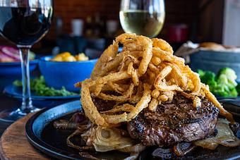 Product: Two top sirloin steaks served on a bed of grilled onions, topped with fried onion strings. Served with 2 sides and a salad - Hoffbrau Steak & Grill House in Amarillo, TX American Restaurants
