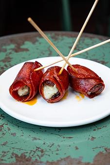 Product: Three pieces of pink chorizo wrapped around brown date speared with toothpicks, on a white plate - Lil’ Ba-Ba-Reeba! in River North - Chicago, IL Bars & Grills