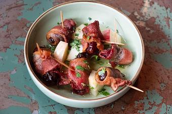 Product: Several brown dates wrapped in brown bacon on toothpicks with apple slices in a small white dish - Lil’ Ba-Ba-Reeba! in River North - Chicago, IL Bars & Grills