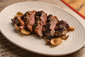 Product: A sliced steak with mushrooms served on a white oval plate - Lil’ Ba-Ba-Reeba! in River North - Chicago, IL Bars & Grills