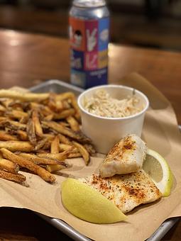 Product: Two pieces of baked Alaskan cod seasoned with smoked paprika, lemon and butter, served with a side of coleslaw and frites with your choice of our signature aiolis or tartar sauce - Longtable Beer Cafe in Downtown Middleton - Middleton, WI American Restaurants