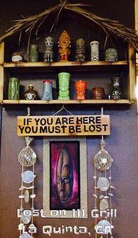 Product: "If you are here you must be lost" sign and a Bamboo Ben tiki shelf with several great tiki mugs on display - Lost on 111 Grill in La Quinta, CA American Restaurants