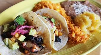 Product: Two flour tortillas filled with smoked pork belly that’s been drizzled with maple syrup and topped with ancho chili pineapple, agave onions, queso fresco, avocado and cilantro. - Que Pasa Cantina in Rapid City, SD Mexican Restaurants