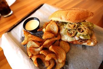 Product: Brisket, pepper jack cheese, fire-roasted poblanos, fried jalapeños, chipotle ranch and red chile sauce served on a bun. Sidewinder fries and chipotle ranch served on the side. - Que Pasa Cantina in Rapid City, SD Mexican Restaurants