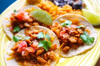 Product: Three white corn tortillas topped with vegan plant-based soy protein, cheese, pico de gallo and cilantro. Black beans and corn cake served on the side. - Que Pasa Cantina in Rapid City, SD Mexican Restaurants