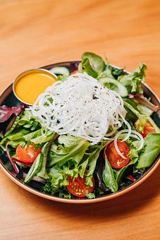 Product: our version of a house salad - greens, cucumber, daikon japanese radish, tomato and carrot ginger dressing - Ramen San in Chicago, IL Japanese Restaurants