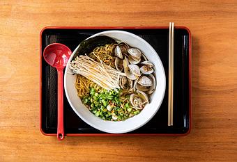Product: a tasty play on linguini and clams, tokyo wavy noodles served in our classic chicken broth, with littleneck clams, mushrooms, scallions, fried garlic, oregano, and some chili flakes and sesame oil for mild spice - RAMEN-SAN Whisky Bar in Fulton Market - Chicago, IL Japanese Restaurants