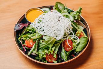 Product: our version of a house salad - greens, cucumber, daikon japanese radish, tomato and carrot ginger dressing - RAMEN-SAN Whisky Bar in Fulton Market - Chicago, IL Japanese Restaurants
