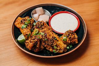 Product: five crispy chicken wings are tossed in a housemade spicy sesame chili sauce. served with fried garlic, pickled japanese daikon radish and lime kosho mayo - RAMEN-SAN Whisky Bar in Fulton Market - Chicago, IL Japanese Restaurants
