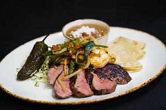 Product: The Ranch Hand
Grilled 6 oz. sirloin steak and 5 shrimp ranchero style with charred peppers
and onions, queso fresco, frijoles charros, chili toreado & flour tortillas - Stables Ranch Grille - Restaurant-Reservations in Tubac, AZ American Restaurants