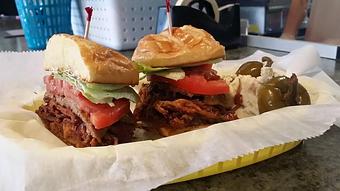 Product: Two Cheddar Cheese grilled patties, BBQ Pulled pork, Applewood Smoked Bacon, Lettuce, Tomato and Garlic Peppercorn Mayo.  Shown with homemade potato salad - Surfwiches Sandwich Shop in Jacksonville Beach - Jacksonville Beach, FL American Restaurants