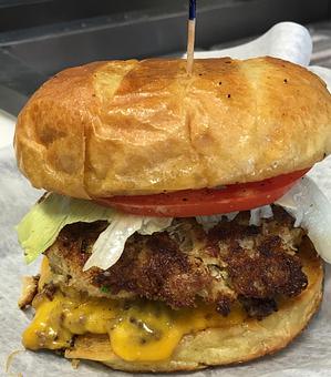 Product: Twin Ground Angus Patties, Cheddar Cheese a Maryland Crab cake on toasted Potato Roll, lettuce, tomato, Old bay tartar Sauce & Garlic Peppercorn Mayo - Surfwiches Sandwich Shop in Jacksonville Beach - Jacksonville Beach, FL American Restaurants