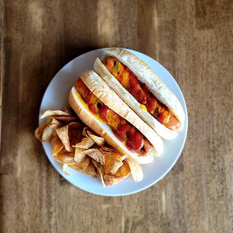 Product: Two marinated and braised carrot dogs with house made ketchup and mustard on a classic bun. Served with house made potato chips and pickles. - The Acre in Albuquerque, NM American Restaurants