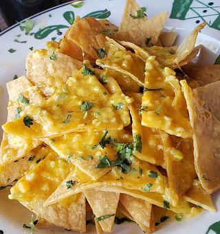 Product: Spicy Nachos!!  With our freshly fried corn tortilla chips dressed in lime and cilantro!  Our nacho sauce is made with a little jalapeno and a little habanero!!  It's crying for our Los Locos Lager! - The Back Door Bakery & Cafe in Sunland, CA American Restaurants