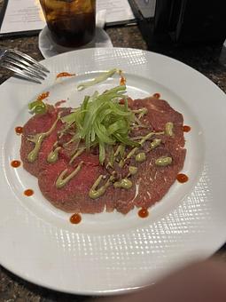 Product: Thinly sliced beef dressed with Parmesan cheese, capers, shaved celery, and a lemon aioli. - The Bowman in Parkville, MD American Restaurants