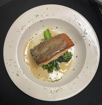 Product: Pan-fried sautéed salmon seated atop sweet broccolini and finished with a miso butter. - The Bowman in Parkville, MD American Restaurants