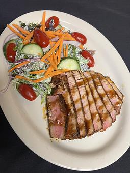 Product: A mixed greens salad (carrot, tomato, red onion, cucumber, avocado) with seared blackened Ahi Tuna. Served in a cucumber-wasabi dressing. - The Bowman in Parkville, MD American Restaurants