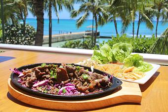 Product: Thinly sliced & marinated beef ribeye served sizzling on a cast iron skillet. Tender Maui butter lettuce, marinated bean sprouts, Nalo Farms honey & ko chu jang dipping sauce, sesame glass noodles & housemade kimchee for you to roll - Tikis Grill & Bar in Waikiki - Honolulu, HI Bars & Grills