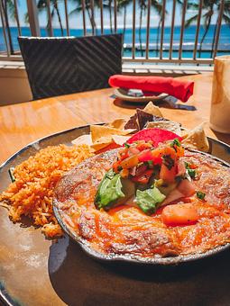 Product: Sauteed bell peppers, onions, housemade green enchilada sauce layered with corn tortillas, cheddar blend, sour cream, avocado, grilled pineapple relish, & Spanish rice - Tikis Grill & Bar in Waikiki - Honolulu, HI Bars & Grills