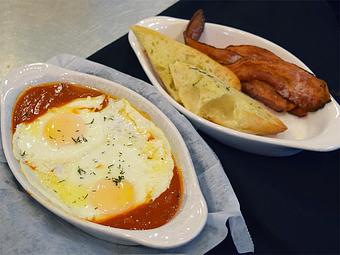 Product: Eggs in Purgatory - Two fried eggs floating on spicy tomato sauce. Served with bacon and toasted French bread. - West Allis Cheese & Sausage Shoppe in West Allis, WI Coffee, Espresso & Tea House Restaurants