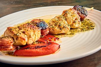 Product: Golden pieces of chicken on a skewer, sprinkled with green herbs and served with a red sauce, on a white plate - Lil’ Ba-Ba-Reeba! in River North - Chicago, IL Bars & Grills