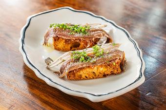 Product: Two pieces of toasted bread topped with a sardine and fresh green herbs on a wooden table - Lil’ Ba-Ba-Reeba! in River North - Chicago, IL Bars & Grills