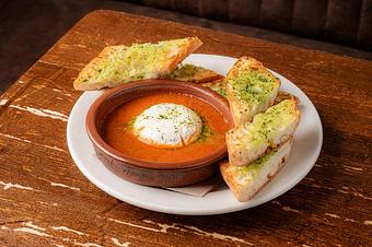 Product: A white piece of cheese with red sauce in a small red dish, on a large white plate with pieces of toasted bread, on a wooden table - Lil’ Ba-Ba-Reeba! in River North - Chicago, IL Bars & Grills