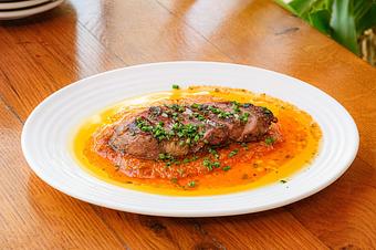 Product: A brown piece of pork sliced into five pieces topped with green herbs on orange and yellow sauce on a white plate - Lil’ Ba-Ba-Reeba! in River North - Chicago, IL Bars & Grills