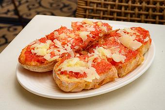 Product: An oval-shaped loaf of bread, sliced in half and topped with red sauce and shavings of cheese, on a small white plate on a white table - Lil’ Ba-Ba-Reeba! in River North - Chicago, IL Bars & Grills