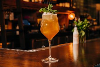 Product: A large wine glass filled with an amber liquid, ice, and garnished with fresh green herbs - Lil’ Ba-Ba-Reeba! in River North - Chicago, IL Bars & Grills