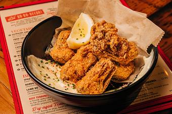 Product: Golden fried artichokes with a lemon and white sauce in a black bowl with brown paper lining - Lil’ Ba-Ba-Reeba! in River North - Chicago, IL Bars & Grills