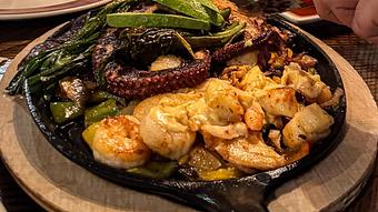 unclassified: Grilled octopus, shrimp, halibut, scallops, skirt steak, and chicken. Drizzled with delicious creamy lobster sauce. - Madaline's Grill & Steak House in Redmond, OR American Restaurants