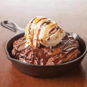 Product: This dessert is for sharing. A warm fudge brownie topped with vanilla bean ice cream and chocolate and caramel sauces. - Big Whiskey's American Restaurant & Bar in Springfield, MO Bars & Grills