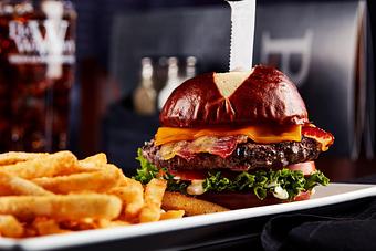 Product: Served on a butter toasted pretzel bun with lettuce, tomatoes, horseradish aioli and topped with cheddar cheese and crisp bacon. - Big Whiskey's American Restaurant & Bar in Springfield, MO Bars & Grills