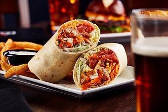 Product: Lightly breaded chicken tossed in our mild buffalo sauce with shredded cheddar cheese, lettuce, tomato and ranch dressing. Wrapped together in a flour tortilla. Served with seasoned fries. - Big Whiskey's American Restaurant & Bar in Springfield, MO Bars & Grills