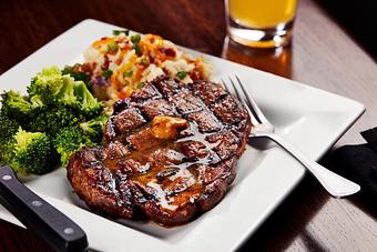 Product: 12 oz. hand-cut ribeye, seasoned and grilled to perfection. Topped with our signature steak butter and served with steamed broccoli and loaded mash potatoes. - Big Whiskey's American Restaurant & Bar in Springfield, MO Bars & Grills