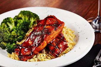 Product: Grilled salmon glazed with a sweet sauce with just a hint of bourbon. Served over rice pilaf and with a side of broccoli. - Big Whiskey's American Restaurant & Bar in Springfield, MO Bars & Grills