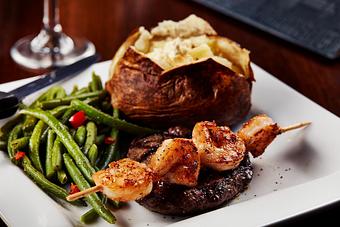 Product: A 6 oz. USDA center cut sirloin, grilled to perfection, with a seasoned grilled shrimp skewer. Served with your choice of potato and steamed vegetables. - Big Whiskey's American Restaurant & Bar in Springfield, MO Bars & Grills