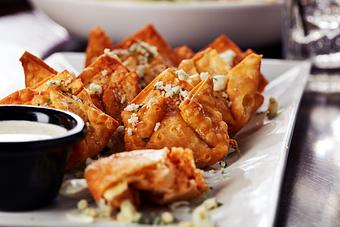 Product: Crispy fried wontons wrapped around pockets of Big Whiskey’s Buffalo Chicken Dip and sprinkled with bleu cheese crumbles. Served with ranch dressing. - Big Whiskey's American Restaurant & Bar in Springfield, MO Bars & Grills