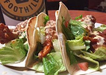 Product: Tacos: Fried chicken tenders tossed in Tennessee hot BBQ sauce, lettuce, diced tomatoes and beer cheese. - Foothills Brewing in Winston Salem, NC American Restaurants