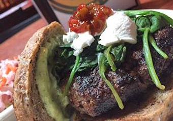 Product: 8oz Beef patty, spinach, goat cheese, roasted garlic, pesto mayo, & pepper relish on spent grain bread. - Foothills Brewing in Winston Salem, NC American Restaurants