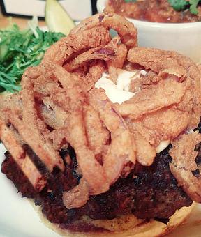 Product: Beef burger with Frisee lettuce, Marscapone cheese, tomato, brown mustard and Fried onion straws. Served on a brioche bun. - Foothills Brewing in Winston Salem, NC American Restaurants