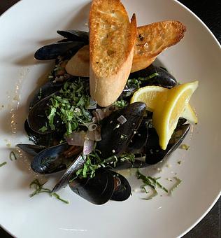 Product: Braised mussels in white wine garlic broth with diced tomatoes and fresh basil. Served with toasted baguettes. - Harvey's Grill and Bar in Saginaw, MI American Restaurants